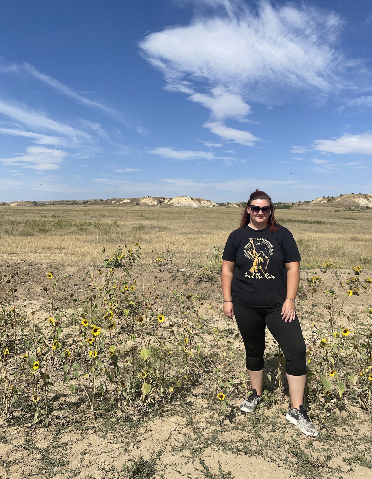 Woman standing next to sunflowers in a field