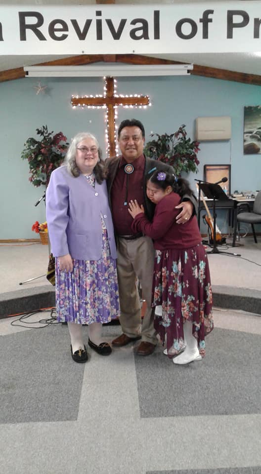 Fred Smith with a woman and child in front of a cross