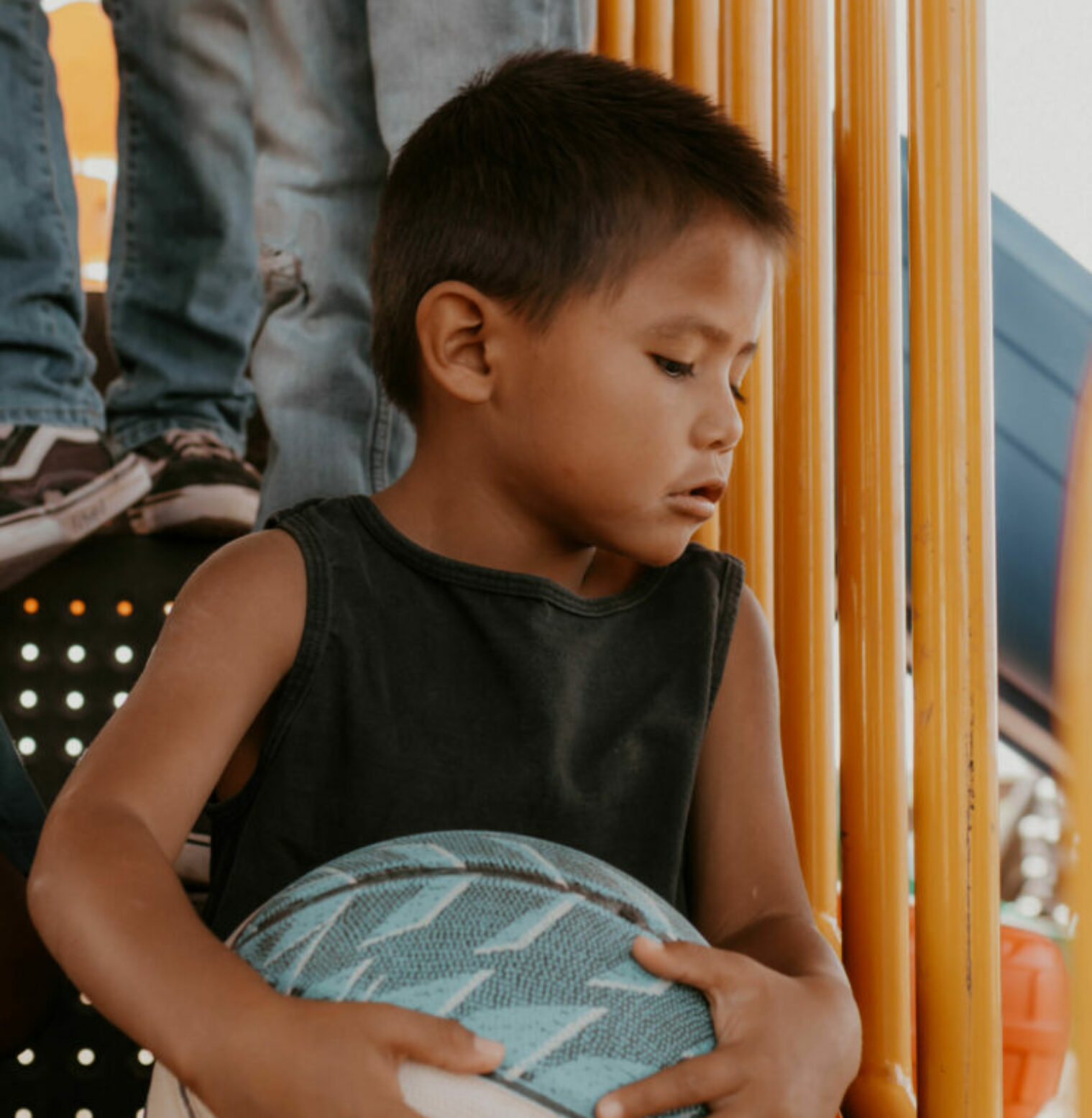 A young boy looks down while holding a basketball